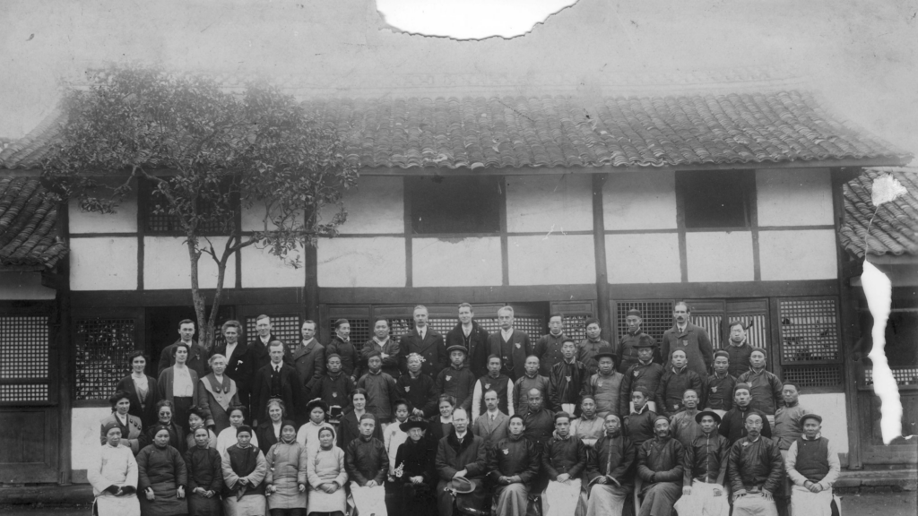 A black and white group photo taken in China with a group of Chinese and non-Chinese people in front of a building.